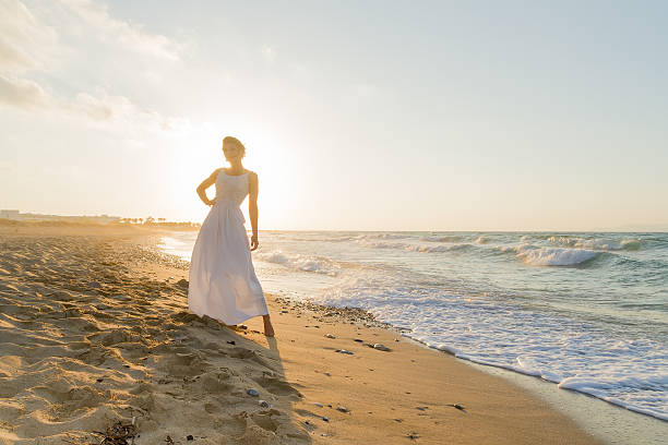 istock Young woman enjoys walking on a hazy beach at dusk. 536722089