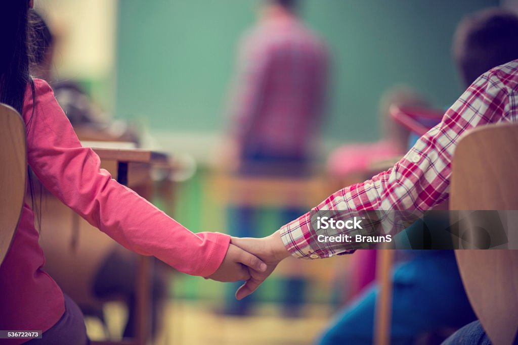 Youth love. Unrecognizable schoolboy and girl holding hands in the classroom. 2015 Stock Photo