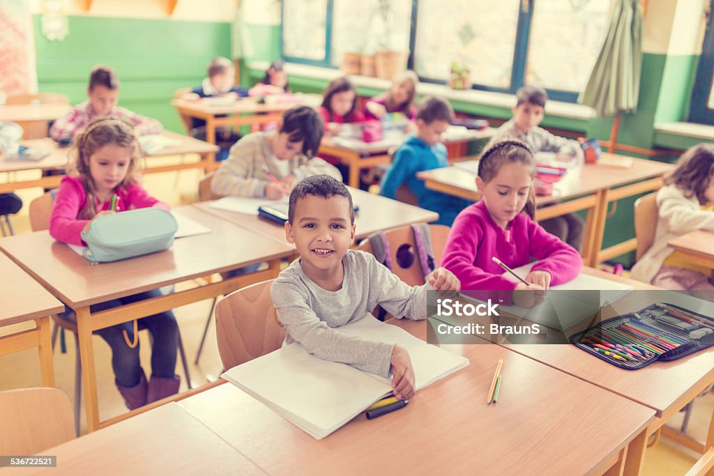 African American schoolboy. Smiling little African American boy sitting in the classroom with his classmates and looking at the camera. 2015 Stock Photo