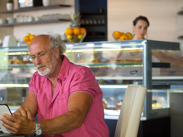 Looking at tablets at the sweets bar Portrait of senior looking at tablets at the sweets bar in Portoroz restaurant, Slovenia. sunken cake stock pictures, royalty-free photos & images