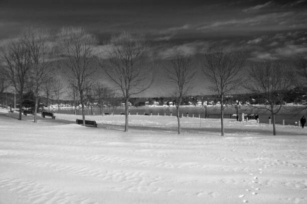 On a sunny frozen day and the ground covered in snow, wooden benches remain empty.