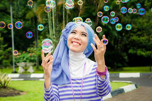 Asian Woman moslem with happy face playing with bubble