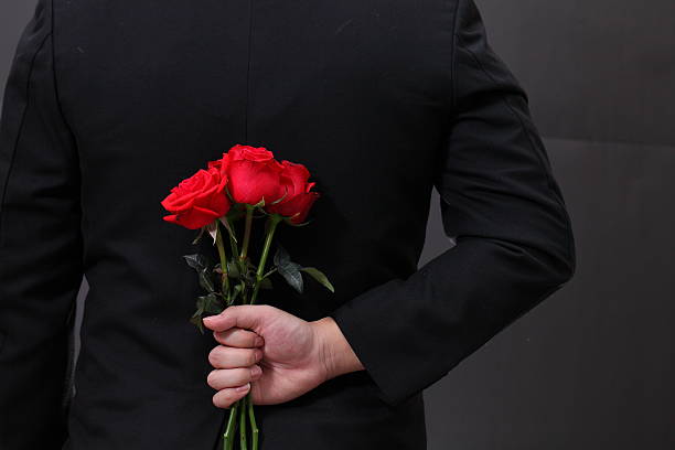 istock Man hiding a red rose flower behind his back. 536725409