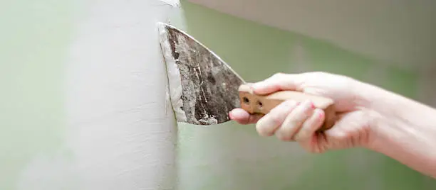 Woman plastering wall at house.