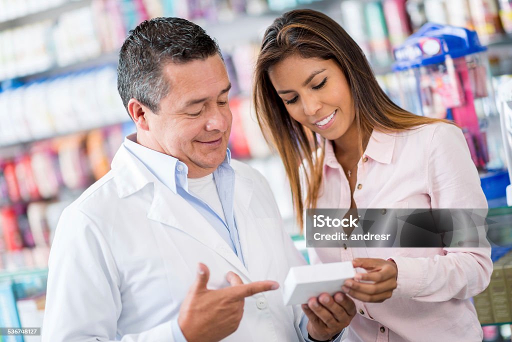 Pharmacist talking to client at the drugstore Pharmacist talking to client at the drugstore and suggesting a medicine 2015 Stock Photo