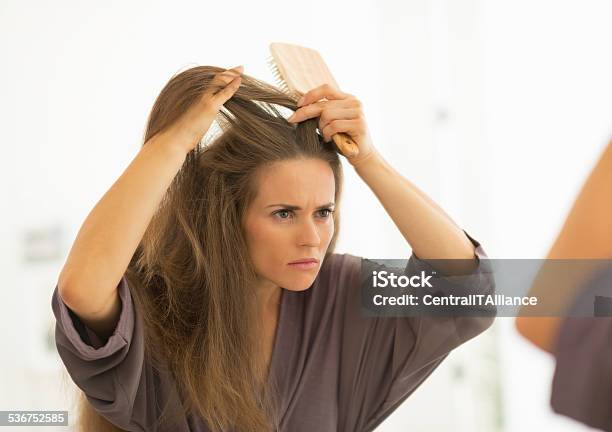 Concerned Young Woman Combing Hair In Bathroom Stock Photo - Download Image Now - Dandruff, Human Hair, Women