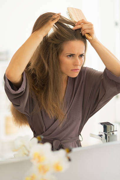 istock concerned young woman combing hair in bathroom 536752587
