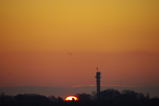 Communication tower in silhouette at sunrise