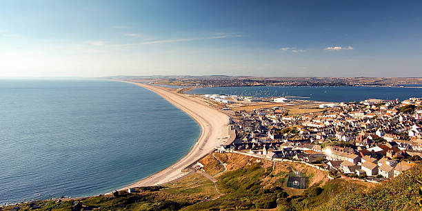 Chesil Beach and Fortuneswell The sweep of Chesil Beach along Lyme Bay seen from the heights of the Isle of Portland, with the town of Fortuneswell and Portland Harbour. weymouth dorset stock pictures, royalty-free photos & images