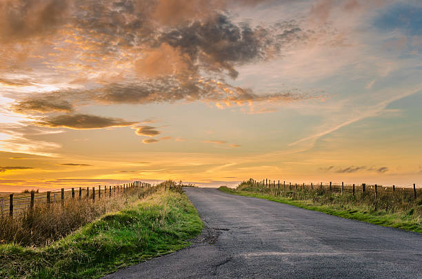 route de campagne au coucher du soleil - country road photos et images de collection