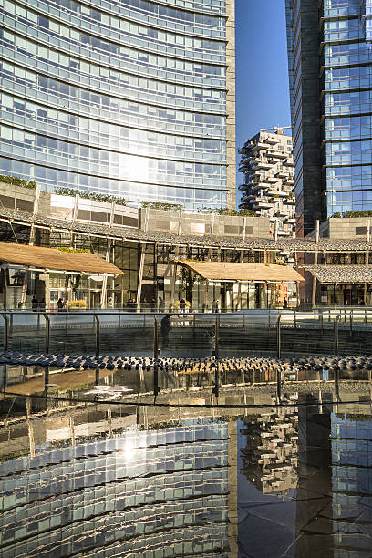 Gae Aulenti square in Milan (Italy) Milano, Italy - November 19, 2014: Gae Aulenti square in Milan (Italy). Partial view of modern square with its lakes. Some people walking on the square. Reflection of buildings on the artificial lakes. In background The "Bosco Verticale" building (winner of International Highrise Award) milan fashion week stock pictures, royalty-free photos & images