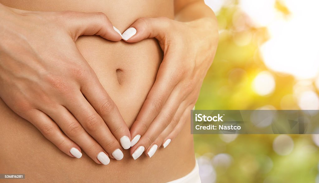 Body care, pregnancy or diet concept Body care, pregnancy or diet concept, female hands forming heart shape on the stomach Healthy Lifestyle Stock Photo