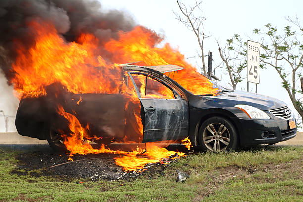 Car fire, burning profusely on New Jersey highway Paramus  New Jersey, USA - May 28, 2016: This Nissan mid size sedan burning profusely on the shoulder of the Garden State Parkway, luckily the driver and all passengers escaped injury. grass shoulder stock pictures, royalty-free photos & images