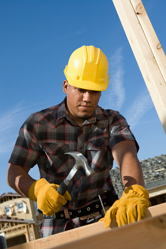 Construction worker hammering nail on construction site