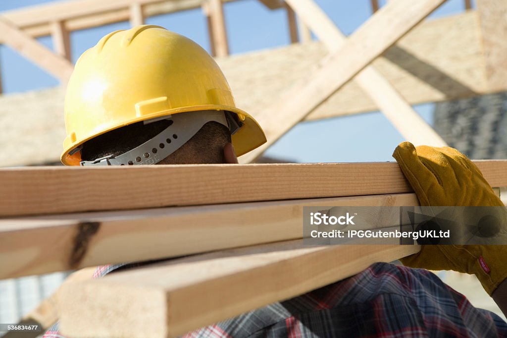 Construction site work Construction worker carrying planks on construction site Construction Site Stock Photo