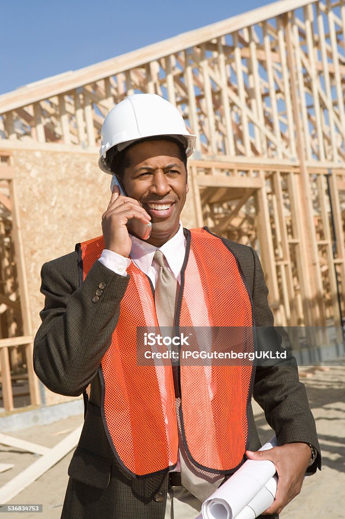 Architect  at Construction site Architect talking on mobile phone holding blueprints 2015 Stock Photo
