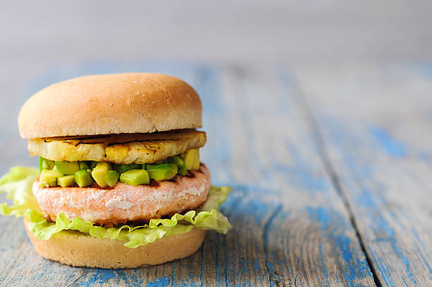 Homemade fish burger with salmon, avocado and pineapple.Close up