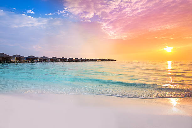 magnifique coucher de soleil au centre de villégiature tropical avec bungalows sur pilotis - maldives photos et images de collection