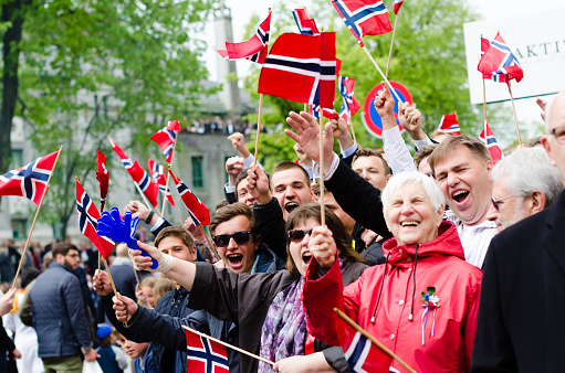 Bergen, Norway - May 17, 2016: People in Bergen, Norway during Constitution Day (17th of May). Adults and children are dressed up in traditional dresses (bunad) and waiving flags at the passing procession.