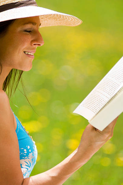 istock Young woman reading book, sitting in meadow 536852765