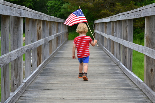 Boy carrying American Flag over bridge