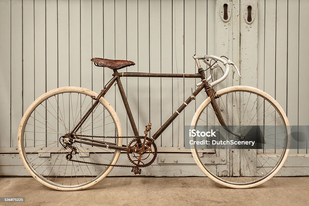 Vintage racing bicycle in an old factory Vintage rusted racing bicycle parked in an old factory with wooden doors 2015 Stock Photo