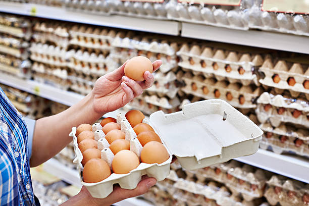 dans les mains de femme dans un supermarché emballage des oeufs - egg photos et images de collection