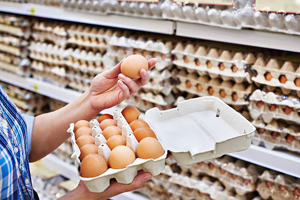 nas mãos de mulher no supermercado de ovos embalagem - eggs imagens e fotografias de stock