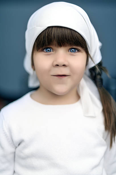 cute little girl with blue eyes and white scarf on her head.