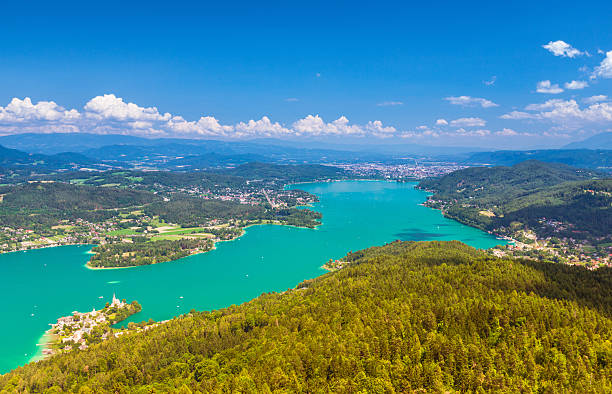 Lake Wörthersee View over the Wörthersee and the villages Maria Wörth, Pörtschach with Austrian Alps and Klagenfurt in the distance pörtschach am wörthersee stock pictures, royalty-free photos & images