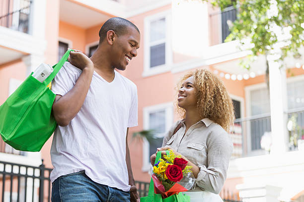 couple transportant des sacs d'achat de denrées alimentaires - vertical single flower women teenager photos et images de collection