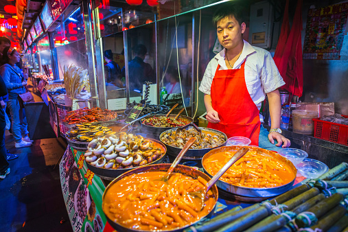 Beijing, China - 27th September 2013: Man cooking and selling traditional street food in a colourful night market in the cowded Wanfujing district of downtown Beijing, China's vibrant capital city.