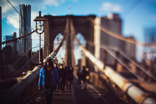 New York City, New York - October 1, 2021: Tourists and locals walking across the famous landmark Brooklyn Bridge which  connects the boroughs of Manhattan and Brooklyn with a view of lower Manhattan.