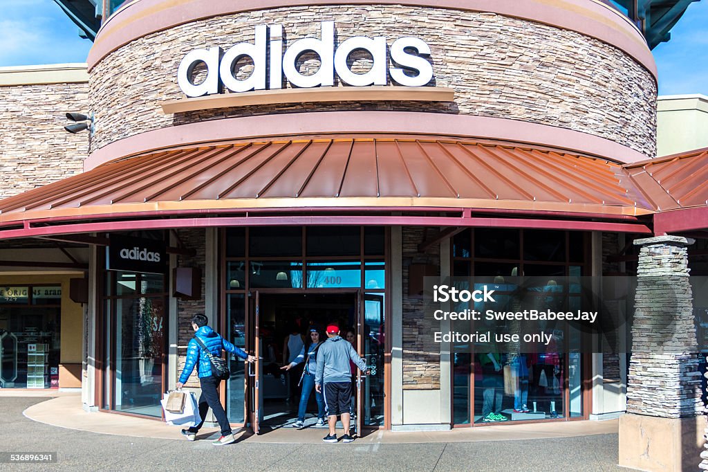 Adidas Store Woodburn, Oregon, USA - January 31, 2015: Customers are going in and out of a Adidas Outlet Store at the Woodburn Outlet Mall in Woodburn, Oregon. Adidas AG is a German multinational corporation that designs and manufactures sports shoes, clothing and accessories. The company is based in Herzogenaurach, Bavaria, Germany. Besides sports footwear, Adidas also produces other products such as bags, shirts, watches, eyewear and other sports and clothing-related goods. Adidas is the largest sportswear manufacturer in Europe and the second biggest in the world. 2015 Stock Photo