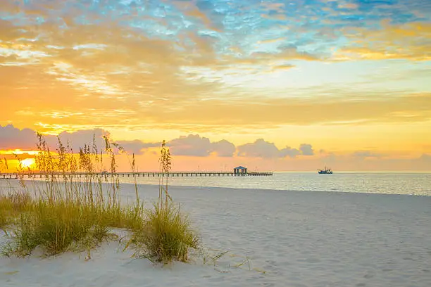 Photo of Gulfport Mississippi beach, dramtic golden sunrise, pier, shrimp boat, bay