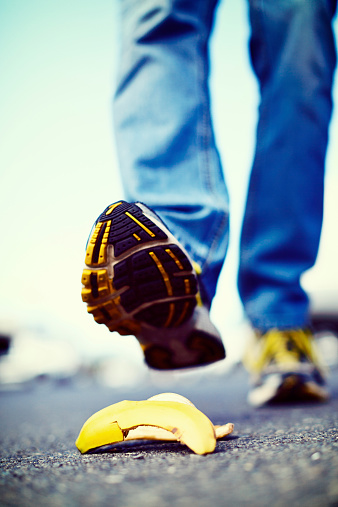 An unidentified  male walker's foot is about to step on a dropped banana peel - a painful accident waiting to happen that could also prove expensive, either in medical care or in insurance claims!