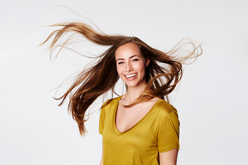 Windblown beauty in white studio, smiling