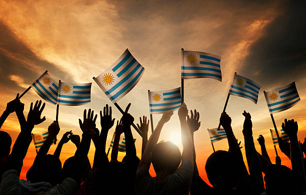 istock Group of People Waving Uruguayan Flags in Back Lit 536951553