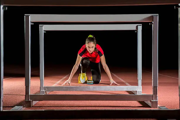 Young athlete on the starting block in hurdles race