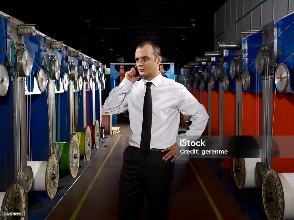 Young Boss talking on phone Young boss talking on the phone in fiber optic cable factory. 2015 Stock Photo