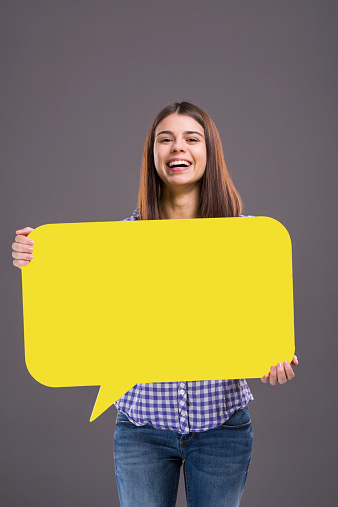 Young girl holding yellow speech bubble.