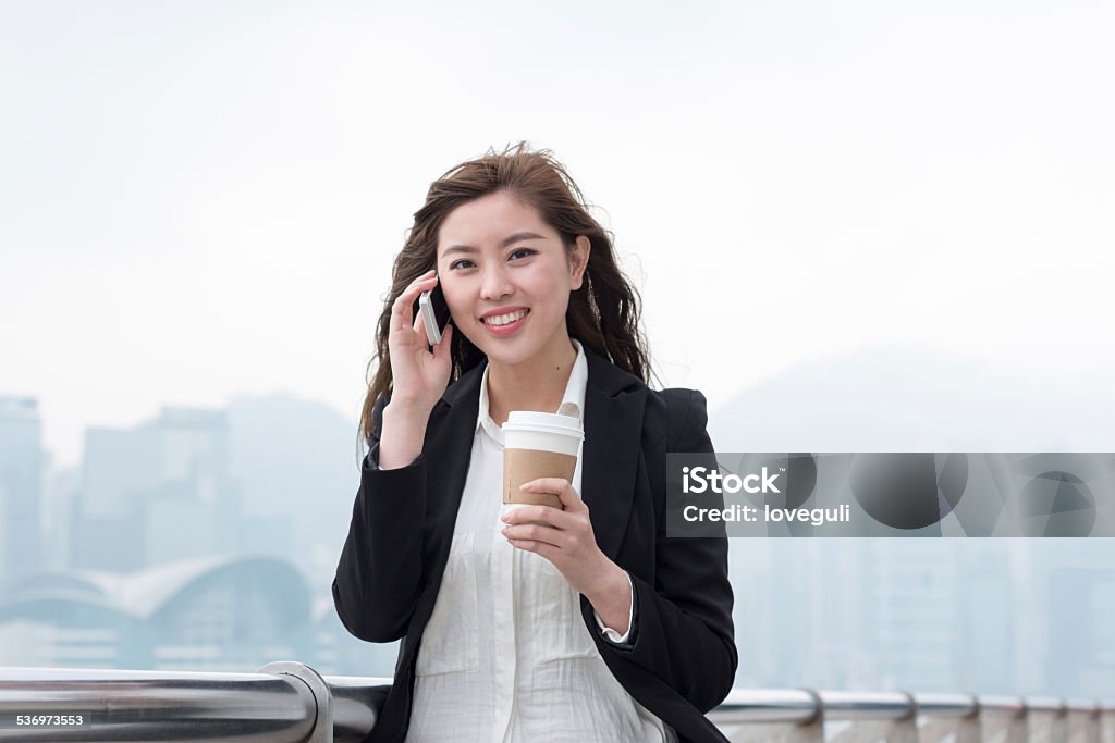 asian successful businesswoman talking on phone asian successful businesswoman talking on phone with cityscape of hong kong as background 2015 Stock Photo