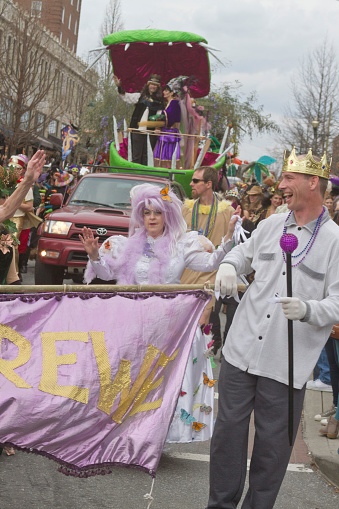 Asheville, North Carolina, USA - March 2, 2014:  People wearing colorful costumes overseen by the King and Queen of Misrule on a float romp in the Spring Mardi Gras parade on March 2, 2014 in downtown Ashevile, NC