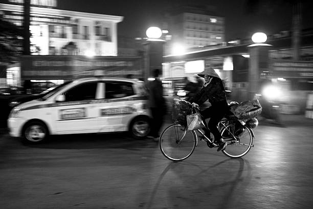 Hanoi, Vietnam - February 9, 2015 : A woman is carrying her loaded bicycle through the city of Hanoi, Vietnam at dawn.
