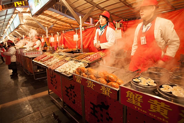 Beijing, China - January 5, 2012: vendors in the market stalls of the Wangfujing Snack Street, a popular shopping place for tourists and residents alike, where a large variety of common and exotic food is offered day and night. Among other local delicacies this stall offers crabs and dumplings