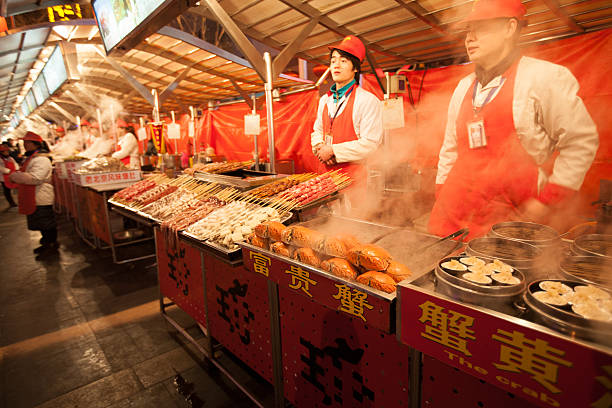 Exotic food market in Beijing, China Beijing, China - January 5, 2012: vendors in the market stalls of the Wangfujing Snack Street, a popular shopping place for tourists and residents alike, where a large variety of common and exotic food is offered day and night. Among other local delicacies this stall offers crabs and dumplings wangfujing stock pictures, royalty-free photos & images