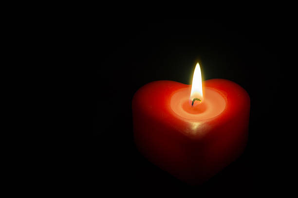 istock Red heart-shaped candle isolated on black. 537015663