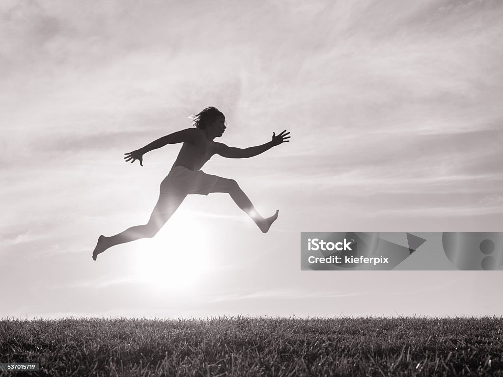 Male runner Silhouette of men jumping through the air. Jumping Stock Photo