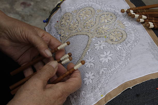 Pescocostanzo's tombolo Pescocostanzo, province of L'Aquila, Italy. The manufacture of pillow lace dates back to the sixteenth century. A municipal school tradition handed down to future generations by teaching the art of bobbin to girls. The school also teaches courses for tourists. spindle stock pictures, royalty-free photos & images