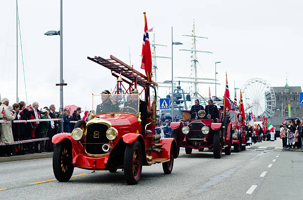 Bergen, Norway - May 17, 2016: Constitution Day parade in Bergen, Norway. The firefighters are driving retro fire trucks in front of the famous Bryggen, a UNESCO heritage site.
